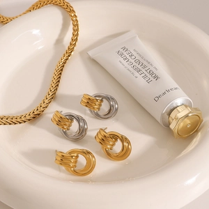 Flat woven gold snake chain and textured hoop earrings on a ceramic jewelry tray