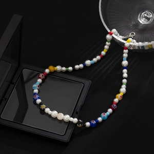 Chic beaded necklace with white pearls and colored glass flowers over a luxury jewelry box