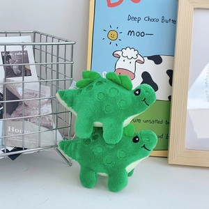 Detailed view of two cute green plush dinosaur toys with soft fabric and embroidered faces