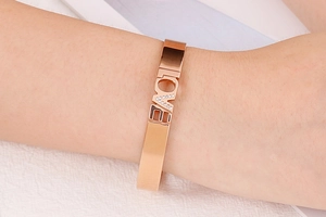 Close-up of rose gold cuff bracelet with LOVE engraving and crystal stone on wrist
