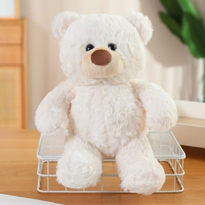 Gros plan d'un ours en peluche blanc doux avec un nez marron sur une table en bois