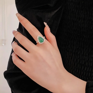 Close-up of heart-shaped green zircon ring with silver-plated band on finger