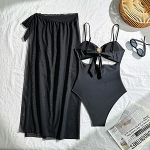 Platliggende zwarte bikini met gouden sterdetail en mesh sarong op een wit laken
