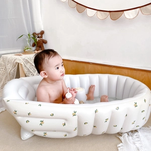 Inflatable white baby bathtub with lemon print and wavy edges in a cozy home setting