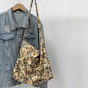 Close-up of floral pattern canvas tote bag hanging on a denim jacket and wood hanger