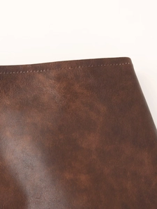 Gros plan sur la texture du similicuir marron et les coutures de la veste rétro