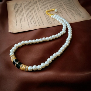 Détail de ce collier ras du cou en perles vintage avec émail noir et strass brillants