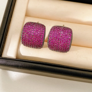 Makroaufnahme quadratischer rosa Zirkonia-Ohrstecker mit dunklem Metall in einer Box