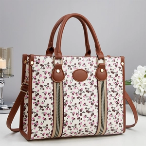 Chic cream tote bag with cherry print, brown top handles and adjustable shoulder strap