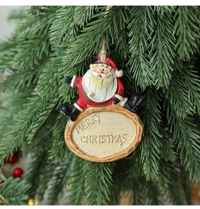 Detail of resin Santa Claus pendant with Merry Christmas sign on a festive tree branch