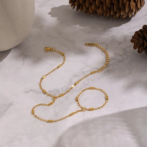 Gros plan d'un bracelet bague doré en acier inoxydable sur marbre avec une pomme de pin