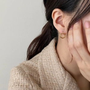 Close-up of elegant double gold hoop earrings worn on a model with a tweed jacket