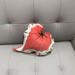 Detailed view of leaf-shaped plush pillow with realistic Caladium vein texture on a grey sofa