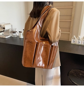 Detail of a brown PU leather tote bag with functional exterior pockets for autumn