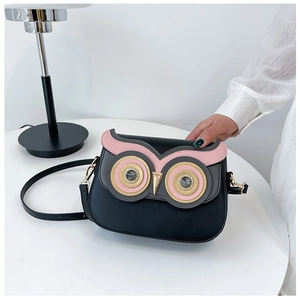 Detail of cute owl face design on black PU leather crossbody bag with golden hardware
