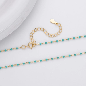 Detail of adjustable gold necklace with turquoise beads and secure lobster clasp