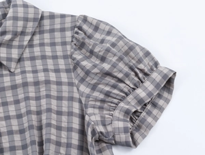 Détail de la robe courte à carreaux gris avec manches bouffantes et col à revers
