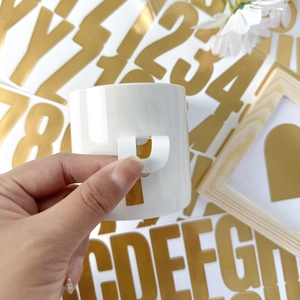 Close-up of gold alphabet stickers on a white mug for a creative DIY decoration project