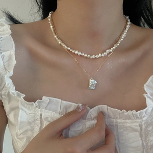 Close-up of double-layered baroque pearl necklace with gold pendant on woman neck
