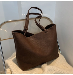 Detailed close-up of dark brown lychee texture leather on a large capacity tote bag