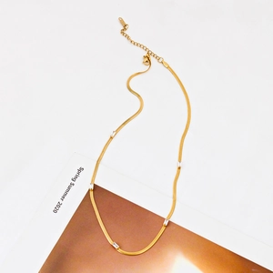 Detail of a gold snake chain necklace with five rectangular clear zircon accents