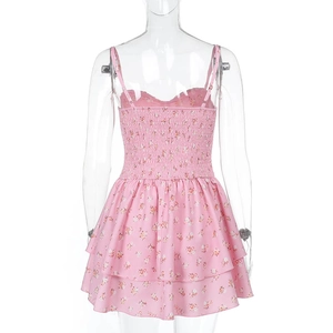 Détail d'une robe fleurie rose avec fines bretelles, dos froncé et ourlet à volants