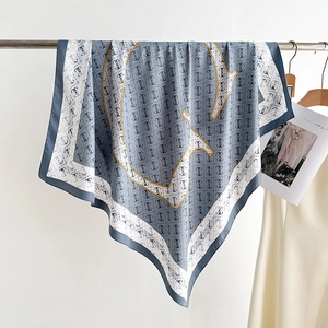 Close-up of grey and white twill silk scarf with repeat pattern and gold line details