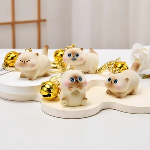 Cute Siamese cat plush keychains with blue eyes and golden bells on a display stand