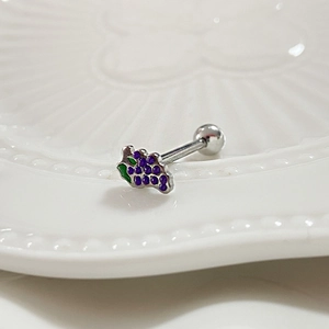 Macro shot of a purple grape-shaped barbell tongue ring on a white ceramic tray