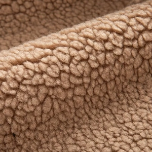 Macro shot of warm camel sherpa fleece texture showing soft thick lamb wool fibers