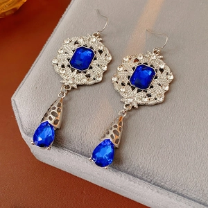 Close-up of vintage silver drop earrings with deep blue sapphires and pavé crystals