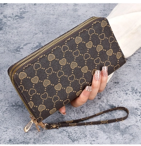 Detail of dark brown long wallet with double gold zippers and heart pattern texture