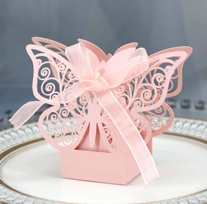 Close-up of pink laser-cut butterfly favor box with ribbon on a decorative plate