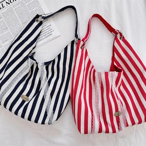 Détail de sacs fourre-tout en toile rayée avec bordure en dentelle et logo métallique