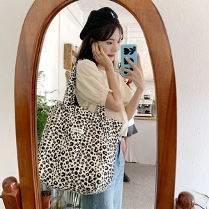 Detail of leopard print canvas tote bag with logo patch in a lifestyle mirror selfie
