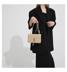Detail of khaki quilted shoulder bag with gold chain and metal tassel on black blazer