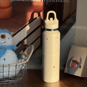 Detail der cremefarbenen Edelstahlflasche mit Hundemotiven und tragbarem Griff