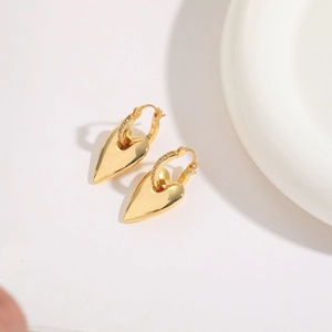 Detail of gold heart earrings with sparkling pavé crystals on a minimalist white backdrop