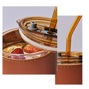 Detail of bamboo joint coffee glass with brown leather sleeve, lid, and straw