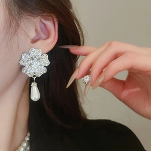Detailed close-up of model wearing floral silver earrings with sparkling crystals and pearls