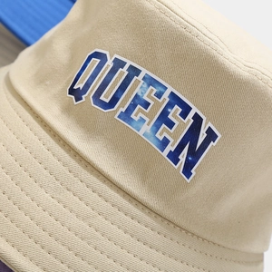 Detailed close-up of QUEEN lettering with galaxy texture on a beige cotton bucket hat
