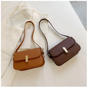 Detail view of brown leather saddle bags with gold square buckles on white fabric