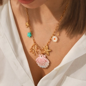 Detail of beach themed gold necklace with starfish, shell and coral pendants worn by model