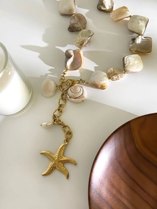 Detail of starfish pendant necklace with natural shells and pearls on gold chain