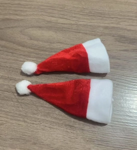 Nahaufnahme kleiner roter Weihnachtsmützen aus Samt für Besteck auf Holzuntergrund