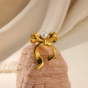 Macro shot of a golden bow ring with a white pearl on a natural stone and beige fabric