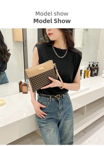 Close-up of stylish clutch bag with geometric pattern and wristlet held by a model