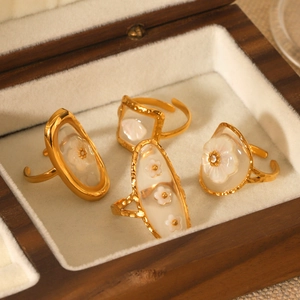 Detail of four gold floral shell rings with mother of pearl and crystal in a jewelry box