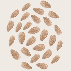 Set of 24 almond shaped glitter gold press-on nails arranged in a circle on beige background