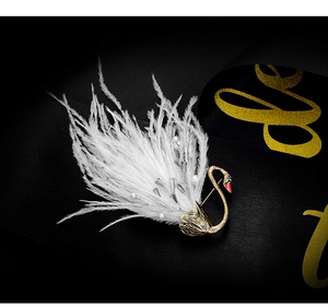 Macro detail of swan brooch with golden neck, white feathers, pearls and crystals